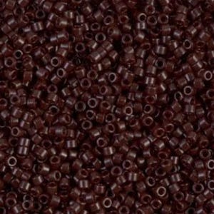 Op de afbeelding: Close-up van een stapel kleine, cilindrische, donkerbruine rocailles. De kralen zijn uniform van grootte en vorm, met een gat in het midden. Ze zijn dicht op elkaar gepakt en creëren een textuur.