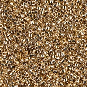 May include: A close-up view of a large quantity of small, gold-colored seed beads. The beads are round and have a shiny finish.