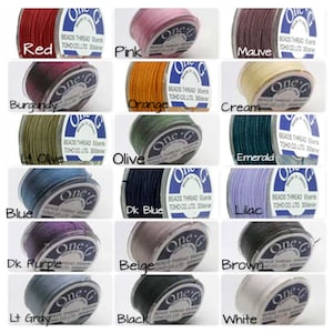 May include: A collection of 18 spools of thread in various colors, including red, pink, mauve, burgundy, orange, cream, light olive, olive, blue, dark blue, lilac, dark purple, beige, brown, light gray, black, and white. Each spool has the text "One-G" and "BEADS THREAD Syards TOHO CO.LTD 300denier" printed on it.