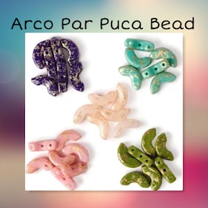Op de afbeelding: Assortiment van Arco Par Puca kralen in verschillende kleuren, waaronder paars, groen, roze en beige. Elke kraal heeft een halvemaanvorm met gouden vlokken.