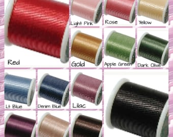 May include: A collection of spools of thread in various colors, including red, gold, light pink, rose, yellow, apple green, dark olive, light blue, denim blue, lilac, purple, natural, brown, and black.