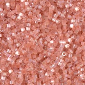 May include: Close-up of a pile of small, translucent, light peach-colored beads. The beads are cylindrical with a slightly iridescent sheen, scattered randomly. The image shows a dense collection of these beads, ideal for jewelry making or crafts.