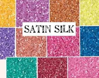 May include: Assortment of small, round, transparent glass beads in various colors, including yellow, purple, orange, pink, blue, green, and red. The beads are labeled "SATIN SILK".