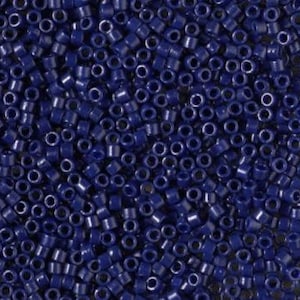May include: A macro shot of many small, dark blue seed beads. The beads are cylindrical with a central hole, closely arranged to fill the image. The colour is a deep, saturated blue, creating a uniform texture across the surface.