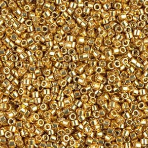 May include: Close-up of a pile of small, cylindrical gold beads. The beads are densely packed together, creating a textured surface. Each bead has a small hole running through its center, and they reflect light, giving them a shiny appearance. Ideal for jewelry making.
