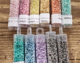 以下が含まれることがあります： カラフルなシードビーズが詰まった透明なプラスチック製の小さなチューブが10本。各チューブには、製品コードと「Forever Beads」と「5g」の文字が書かれたラベルが付いています。