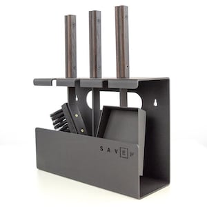 Peut inclure: Un ensemble d'outils de cheminée en métal gris foncé avec trois outils à manche en bois. L'ensemble comprend une brosse, une pelle à poussière et un support avec le mot "SAVEN" imprimé sur le devant. Les outils sont conçus pour être accrochés au mur.