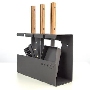 Peut inclure: Un support d'outils de cheminée en métal gris foncé avec trois outils à manche en bois. Le support a une forme rectangulaire avec un compartiment intégré pour une brosse et d'autres outils. Le mot "SAVEN" est imprimé sur le devant.