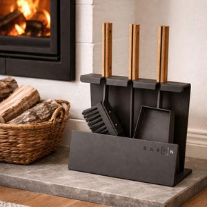 Könnte beinhalten: Ein schwarzes Kaminwerkzeug-Set mit Holzgriffen und einem passenden Ständer. Das Set enthält eine Bürste, eine Schaufel und einen Schürhaken. Das Wort "SAVEN" ist auf der Vorderseite des Ständers aufgedruckt. Ein Korb mit Brennholz steht daneben.