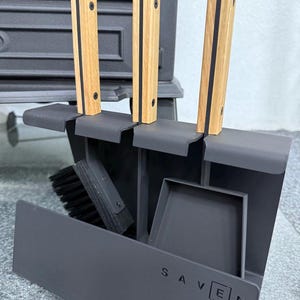 Könnte beinhalten: Ein schwarzes Kaminwerkzeug-Set mit Ständer. Das Set enthält eine Bürste, eine Schaufel und drei Werkzeuge mit Holzgriffen und schwarzen Akzenten. Das Wort "SAVEN" ist auf der Vorderseite des Ständers aufgedruckt.