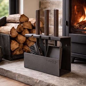 Può includere: Un set di attrezzi per camino grigio scuro con spazzola, paletta e attizzatoio. Il set include un supporto con tre accenti in legno e la scritta "SAVE". Legna da ardere impilata nelle vicinanze.