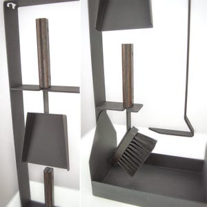 Op de afbeelding: Een donkergrijze metalen haardgereedschapsset met houten handvatten. De set bevat een schop, borstel, pook en een standaard met een plank. De borstel heeft zwarte borstelharen. De standaard is ongeveer 100 cm hoog.