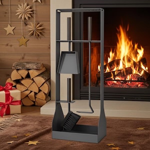 Può includere: Un set di attrezzi per camino grigio scuro con paletta, spazzola e attizzatoio, in un supporto verticale. Gli attrezzi sono esposti davanti a un camino con fuoco.