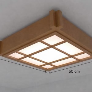 May include: A square, wooden ceiling light fixture with a grid pattern and a warm, natural finish. The fixture is 19.7 inches wide and 3.5 inches tall. The light panels are illuminated, creating a soft glow. The design is reminiscent of Japanese-inspired decor.