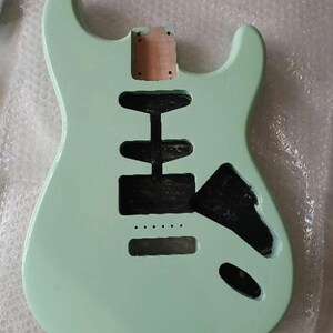May include: A solid body electric guitar body finished in a light mint green color. The body features a double cutaway design with a natural wood neck pocket and several black-painted routed cavities for pickups, a bridge, and electronic controls.