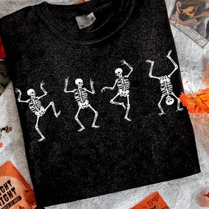 Pu&ograve; includere: T-shirt nero con un disegno di danza di scheletri bianchi. Gli scheletri sono in pose diverse, con gabbie toraciche e teschi dettagliati. La maglietta &egrave; realizzata in materiale morbido, ideale per Halloween o eventi a tema.