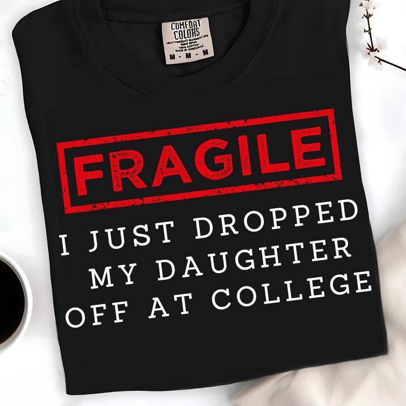 May include: Black t-shirt with the text "FRAGILE" in a red rectangle, and the words "I JUST DROPPED MY DAUGHTER OFF AT COLLEGE" in white. The shirt has a Comfort Colors tag.