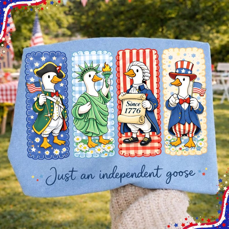 May include: Light blue decorative pillow featuring four cartoon geese dressed in patriotic attire. Each goose represents a different historical figure, holding flags and scrolls. The text "Just an independent goose" is written across the bottom.