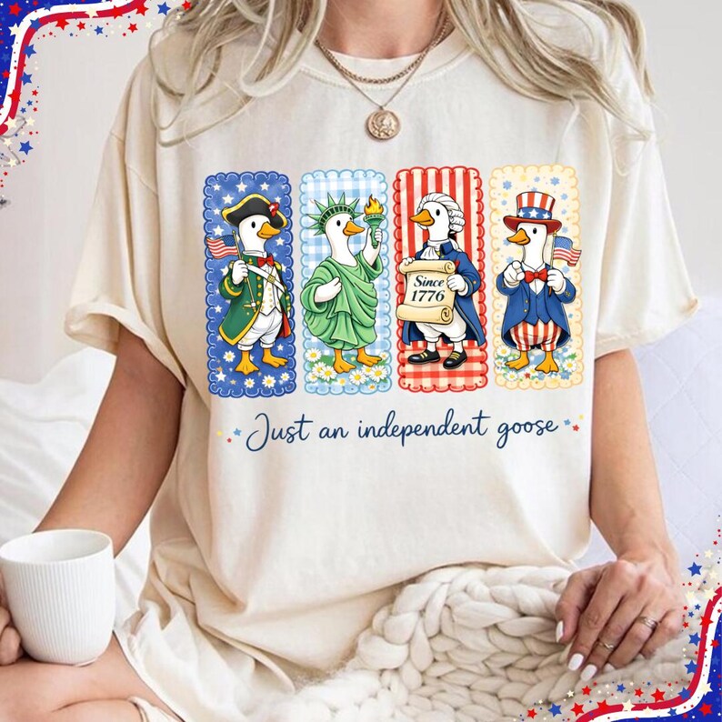 May include: Cream-colored t-shirt featuring four cartoon geese dressed in patriotic attire. Each goose is in a rectangular frame with a different design. The text "Just an independent goose" is below the geese.