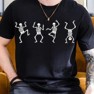 Pu&ograve; includere: T-shirt nera con quattro figure di scheletri bianchi in pose di danza. Gli scheletri hanno la scritta "FUCK TRUMP" stampata sulle loro gabbie toraciche. La maglietta ha maniche corte e girocollo.