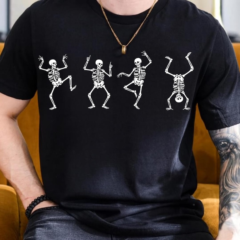Pu&ograve; includere: T-shirt nera con quattro figure di scheletri bianchi in pose di danza. Gli scheletri hanno la scritta "FUCK TRUMP" stampata sulle loro gabbie toraciche. La maglietta ha maniche corte e girocollo.