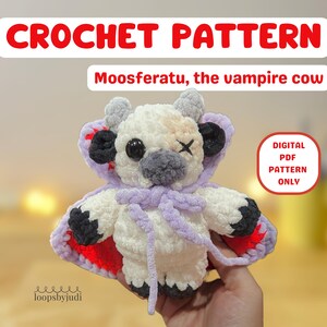 Puede incluir: Peluche de vaca de ganchillo, llamado "Moosferatu, la vaca vampiro", con cuerpo blanco, hocico gris y ojos negros. Lleva una capa morada con detalles rojos y una cruz cosida en un ojo. Incluye el texto "CROCHET PATTERN" y "DIGITAL PDF PATTERN ONLY".