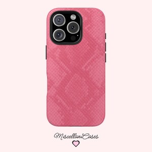 May include: A pink phone case with a snakeskin texture. The case has a camera cutout with three lenses and a flash. The brand name "Miscellani Cases" is written in cursive at the bottom.