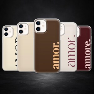 Op de afbeelding: Een verzameling van vijf iPhone-hoesjes in verschillende kleuren, waaronder crème, bruin en bordeauxrood. Elk hoesje heeft het woord "amor" of "amore" in een verticale lettertype. Donkere achtergrond.