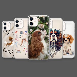 Könnte beinhalten: Eine Sammlung von fünf Handyhüllen mit Cavalier King Charles Spaniels. Die Hüllen zeigen verschiedene Designs, darunter Illustrationen und Fotografien der Hunde. Die Hüllen sind in einer Reihe angeordnet, jede mit einem anderen Design, vor einem dunkelgrauen Hintergrund.