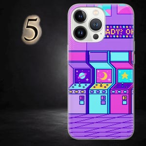 May include: A phone case with a pixelated arcade game design in purple, blue, and pink. The case has a glossy finish and a protective bumper. The design includes a planet, moon, and star. The text "ADY: OH" is visible.