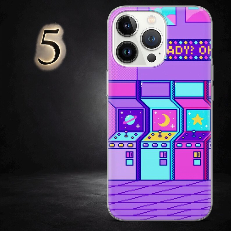May include: A phone case with a pixelated arcade game design in purple, blue, and pink. The case has a glossy finish and a protective bumper. The design includes a planet, moon, and star. The text "ADY: OH" is visible.