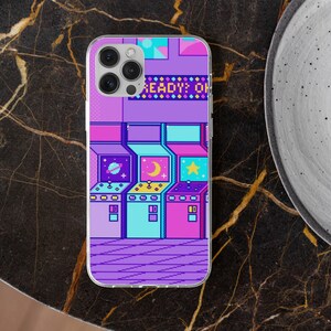 May include: Clear phone case with a pixelated arcade game design in purple, blue, and pink. The design shows three arcade machines with space, moon, and star graphics. The text "READY? ON" is displayed at the top of the case.