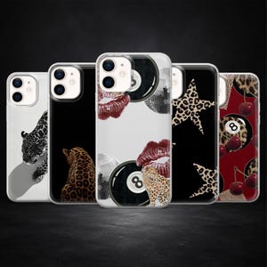Puede incluir: Una colección de fundas para teléfonos con varios diseños. Las fundas presentan imágenes de un leopardo, una bola de discoteca, una bola de billar, una estrella y cerezas. Las fundas tienen un fondo negro.