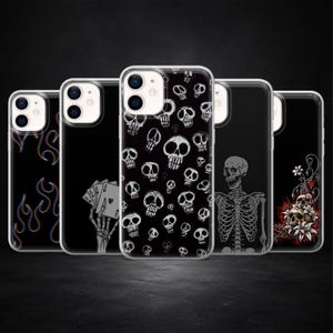 Könnte beinhalten: Eine Sammlung schwarzer Handyhüllen mit verschiedenen Designs. Eine Hülle zeigt ein Flammendesign, eine andere eine Skeletthand, die Spielkarten hält, und weitere zeigen Schädel- und Skelettgrafiken. Die Hüllen sind aus transparentem Kunststoff.