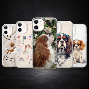 Könnte beinhalten: Eine Sammlung klarer Handyhüllen mit Cavalier King Charles Spaniels. Die Hüllen zeigen verschiedene Designs, darunter Illustrationen und Fotografien der Rasse. Die Hüllen sind in einer Reihe angeordnet und präsentieren die verschiedenen künstlerischen Stile und Hundeporträts.