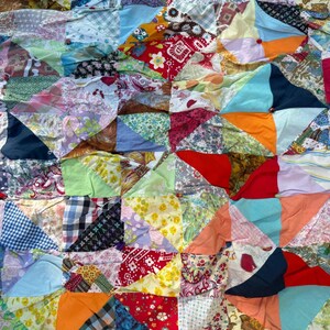 May include: A multi-colored patchwork quilt constructed from various fabric squares featuring diverse patterns including floral, gingham, paisley, and solid colors. The quilt is assembled with small buttons at the center of each four-patch block.