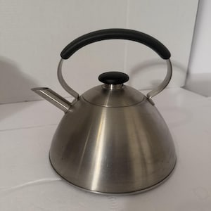 May include: Stainless steel stovetop kettle with a black handle and lid knob. The kettle has a spout for pouring and a curved handle for easy lifting. The kettle is designed for heating water on a stovetop.