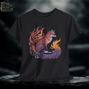 May include: Black t-shirt featuring a detailed illustration of a fox with fiery orange, purple, and yellow accents. The fox is depicted with a long, flowing tail and is surrounded by stylized flames. The shirt has the logo "WYRM & WICK" in the upper left corner.