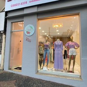 May include: Exterior shot of a boutique named "Divas Boutique" with a sign in pink letters. The storefront features a glass display with mannequins showcasing clothing. The address "804" is visible on the building.