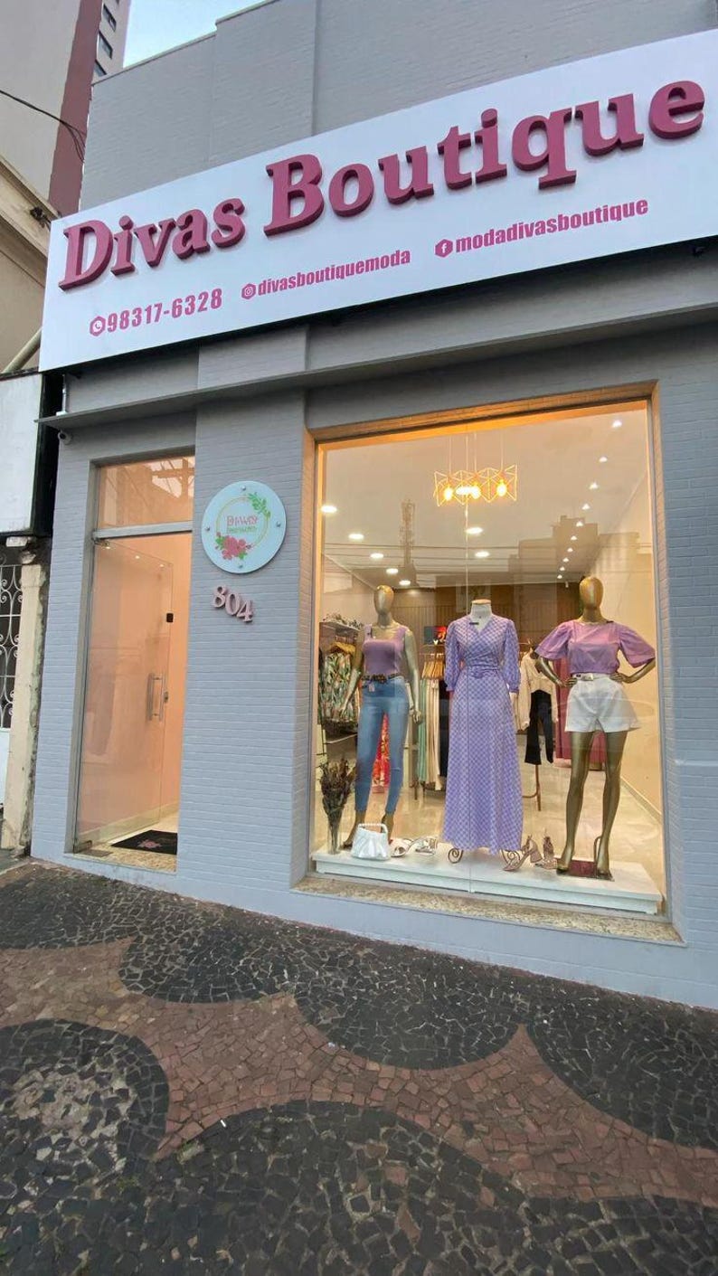 May include: Exterior shot of a boutique named "Divas Boutique" with a sign in pink letters. The storefront features a glass display with mannequins showcasing clothing. The address "804" is visible on the building.