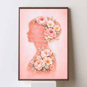 May include: A framed art print featuring a silhouette of a woman's profile adorned with floral arrangements. The artwork is in soft pink hues, with text that reads "Soft is strong, You are safe, Rest is allowed, Love lives here, Bloom slowly."