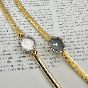 May include: Two gold-tone wristwatches with flexible link bands. One watch features a white dial with the text Pulsar Quartz and a diamond-accented bezel. The second watch has a black dial and a diamond-accented bezel. Both have teardrop-shaped cases.