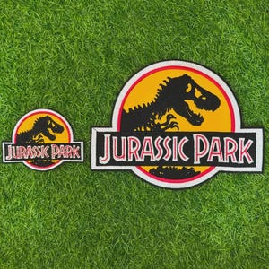 May include: Two embroidered patches featuring the Jurassic Park logo. Each patch displays a black silhouette of a Tyrannosaurus Rex skeleton against a yellow circular background, bordered by red and white, with the text JURASSIC PARK in black.
