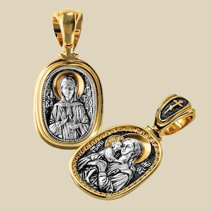 May include: Two gold-coloured pendants with religious iconography. One pendant features a woman with text, the other depicts a woman holding a child. Both pendants have a gold frame and a silver-coloured centre.