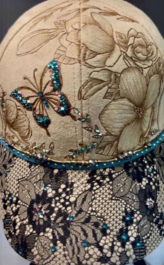 Bling Butterfly Magnolias, hand-burned using a wood burner. Vegan suede adjustable slide back ball cap. Black lace brim. Wearable art!