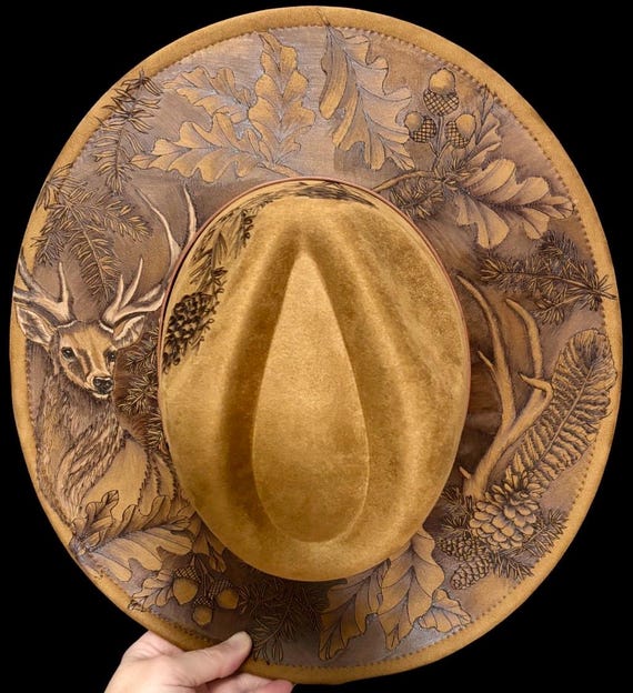 Deer in the woods. Hand-Burned Faux Suede khaki brown wide brim hat. Highly detailed, pheasant feather, pine, oak, permanent paint on deer.