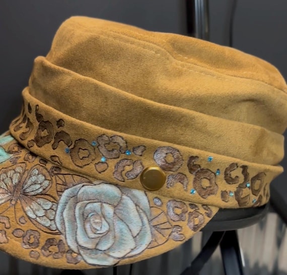Hand-Burned flowers, butterflies, and cheetah print, newsboy style cap, Vegan Suede, Metallic Teal and blue Accent paint and rhinestones.
