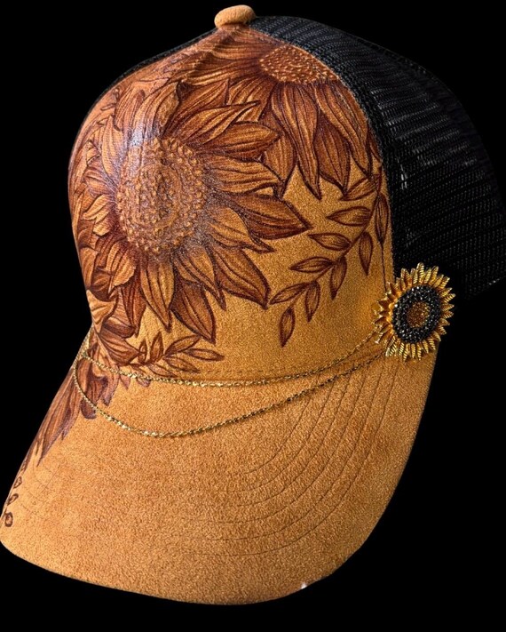Free-hand, hand-burned sunflowers on Vegan (faux) suede ball cap. Sunflower rhinestone gold chain is detachable, black mesh back.