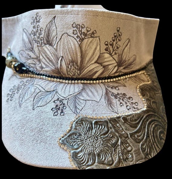 Elegant magnolia, hand burned floral design. Vegan (faux) suede light grey visor. Tooled faux leather and rhinestones.