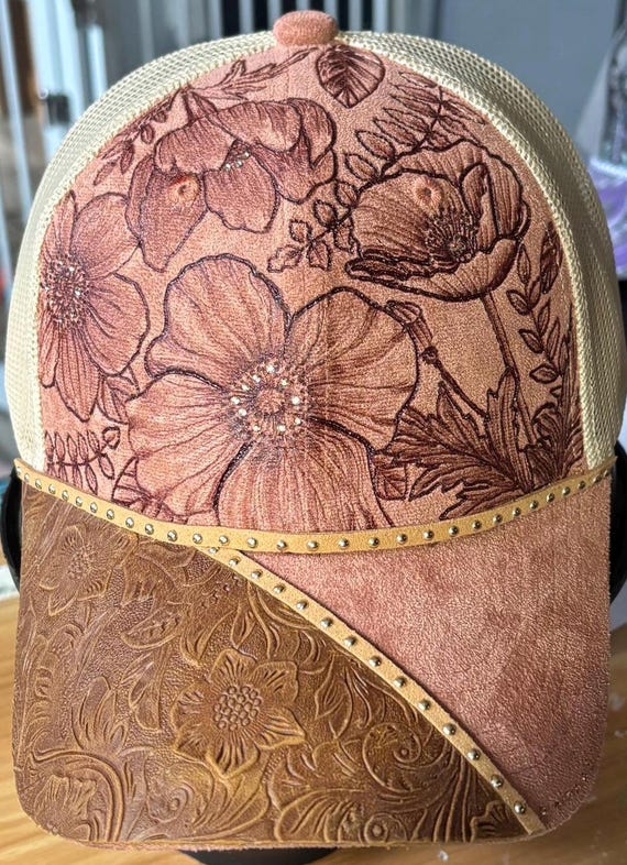 Dusty pink floral design, hand-burned using a hand held wood burner. Champagne colored rhinestones and faux leather, tan mesh ponytail back.